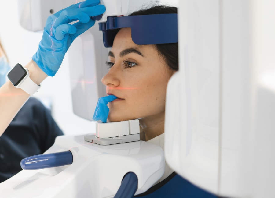 A patient sits with their face in a 3D iCAT Scan machine.