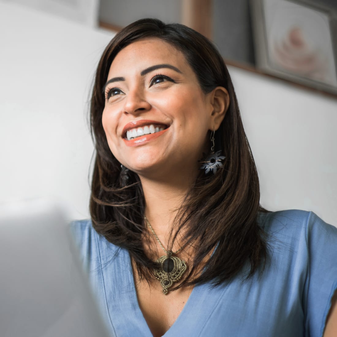 A woman with bright white teeth smiles at a man while she holds a take-out coffee cup.